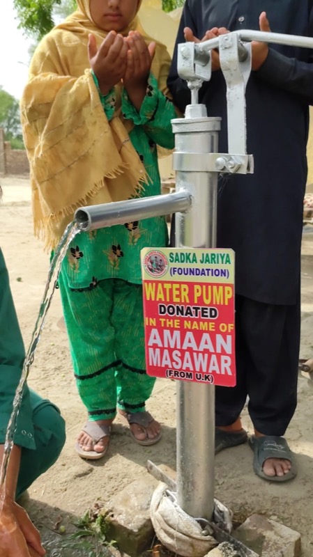 A child giving thanks at a freshly fitted hand pump